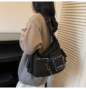 Close-up of black canvas motorcycle bag with silver rivets and decorative chain detail