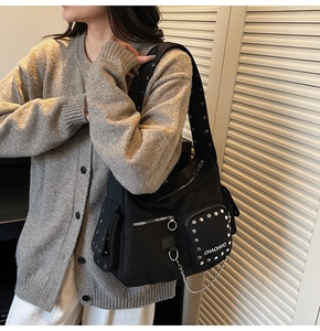 Close-up of black rivet handbag with chain decor and metallic zipper details