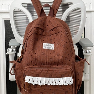 Brown corduroy backpack with cute bear prints and polka dots on a white chair