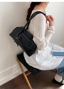 Détail du sac à bandoulière noir avec coutures contrastées et charm étoile