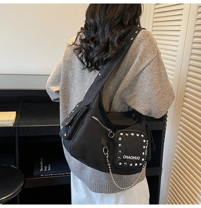 Detailed view of black canvas crossbody bag with silver studs and chain decoration