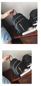 Detail view of a black nylon mini backpack with gold zippers on a wooden table