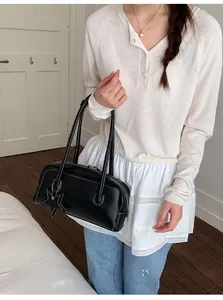 Détail du sac à bandoulière en similicuir noir avec pendentif étoile et coutures blanches