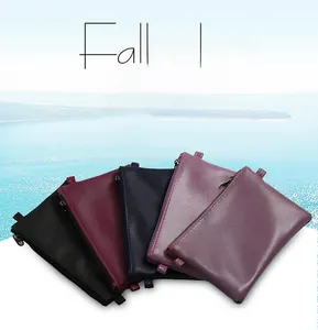 Detail view of colorful leather clutch bags in black, burgundy, and navy with wrist straps