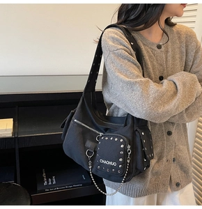 Close-up detail of silver rivets and metal chain on a black canvas motorcycle crossbody bag