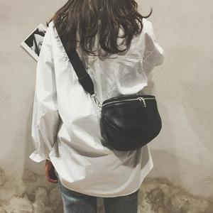 Rear view of model wearing a black matte leather crossbody bag with wide nylon strap