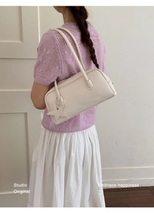 Détail du sac à bandoulière blanc avec breloque étoile et fermeture éclair sur pull violet