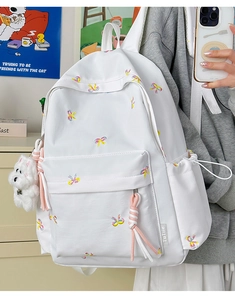 Detail of white backpack with colorful bow embroidery and a cute plush puppy pendant
