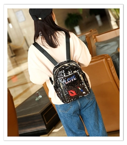 Detail of a mini black sequin backpack with LOVE lettering and red lip embroidery patch