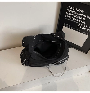 Detail of black canvas motorcycle bag with silver rivets and metal chain decoration