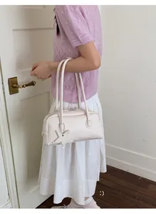 Détail du sac à bandoulière crème avec pendentif en étoile et fermeture éclair
