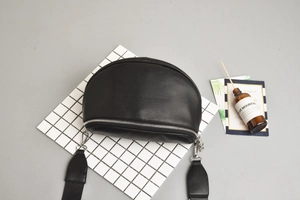 Detail of black semi-circular crossbody bag with smooth leather finish and silver zipper