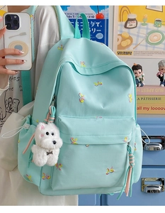Detail of mint green backpack with colorful bow embroidery and a cute plush dog charm