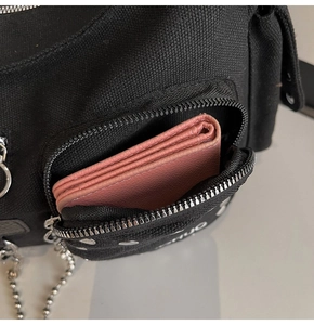 Detail of black canvas motorcycle bag with silver studs and chain showing front pocket capacity