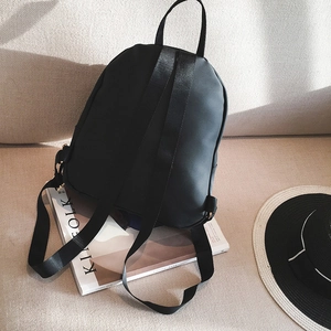 Minimalist black lightweight nylon backpack with adjustable straps on a soft sofa