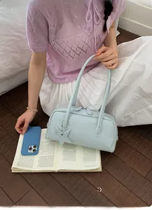Détail du sac baguette en cuir bleu clair avec charme étoile et pull en maille violet