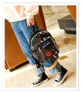 Detail of a black sequin backpack with red lip and LOVE embroidery on a model