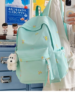 Detailed embroidery of colorful butterflies on mint green canvas backpack with plush charm