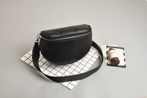 Detailed top view of black crescent moon chest bag on white tile with decor