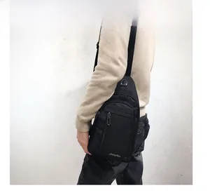 Detail of black crossbody chest bag featuring built-in headphone port and durable strap