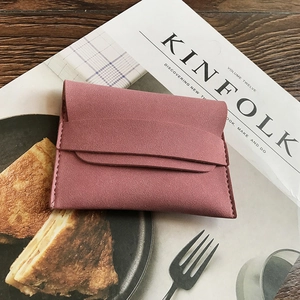Minimalist matte dusty rose envelope coin purse with hand-stitched details on wooden table