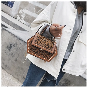 Detail der Schultertasche mit Leopardenmuster, Goldnieten und Kettenriemen am Model gezeigt