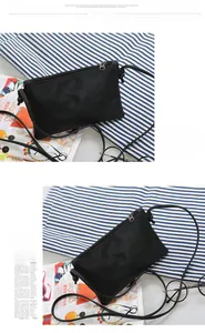 Detail of black pebbled leather crossbody bag with metal zipper and fashion accessories