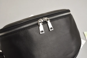 Close-up of black leather chest bag featuring premium silver double metal zippers
