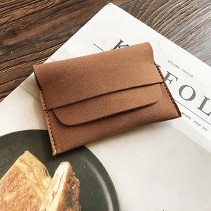 Minimalist brown matte leather envelope coin purse and mini wallet on a rustic wooden table