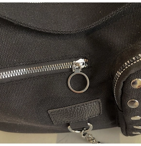 Detail of black canvas bag featuring silver rivets and textured leather patchwork