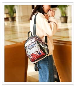 Detail of vibrant sequin backpack featuring embroidered LOVE letters and red lip patterns