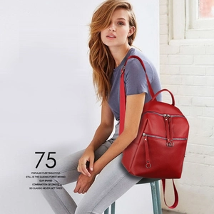 Detail of red faux leather backpack with silver ring zippers and multiple pockets