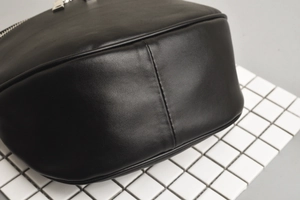 Detailed macro view of black leather texture and reinforced side stitching on fanny pack