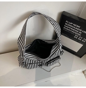 Detail of black and white striped punk shoulder bag with silver chains and zippers