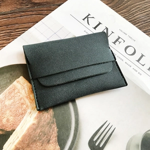 Minimalist matte dark green leather envelope coin purse on a wooden table setup