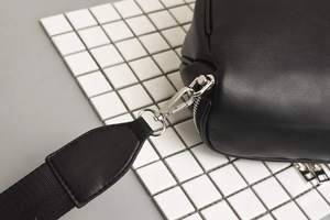 Close-up of silver metal clasps and textured black leather on the sports chest bag strap