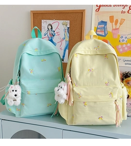 Detail of mint green and yellow canvas backpacks featuring colorful butterfly embroidery