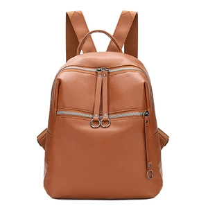 Detailed macro view of brown pebbled leather texture and silver ring zipper on backpack