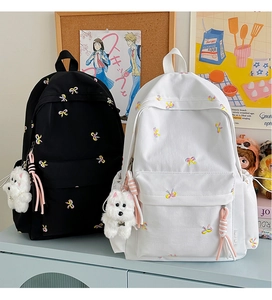 Detail of embroidered colorful bows on a backpack with a cute white puppy plush charm