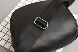 Detailed close-up of the black leather waist bag with silver metal adjustable strap buckle