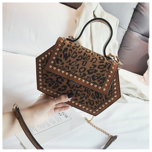 Modische Handtasche mit Leopardenmuster, Nieten und geometrischer Form in der Hand