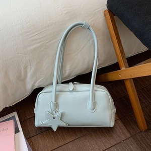 Sac à bandoulière bleu clair avec pendentif étoile sur un sol en bois foncé