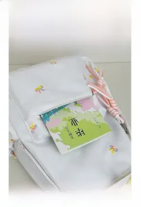 Detail view of the white canvas backpack front pocket with colorful bow embroidery