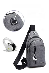 Detail of gray canvas cross-body chest bag featuring a functional sport headphone hole