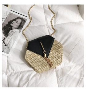 Detail shot of hexagonal straw crossbody bag with black leather flap and gold tassel