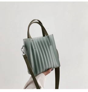 Détail du sac cabas plissé vert menthe avec des anses en cuir vert foncé contrastées