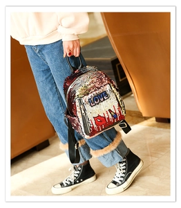 Detail of red and gold sequin backpack featuring embroidered LOVE letters and red lip patches