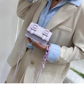 Mini lavender crossbody bag with glossy finish and decorative chain detail on a model