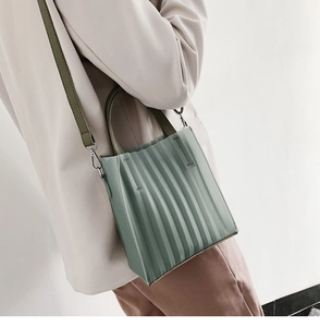 Détail du sac plissé vert clair avec poignées foncées sur un mannequin en costume