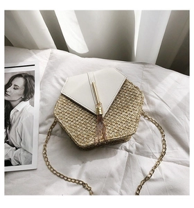 Detailed close-up of straw woven hexagonal crossbody bag with tassel and gold chain